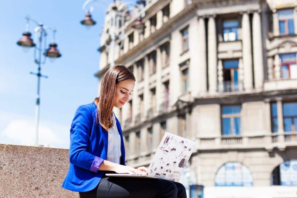 woman sits street works with laptop